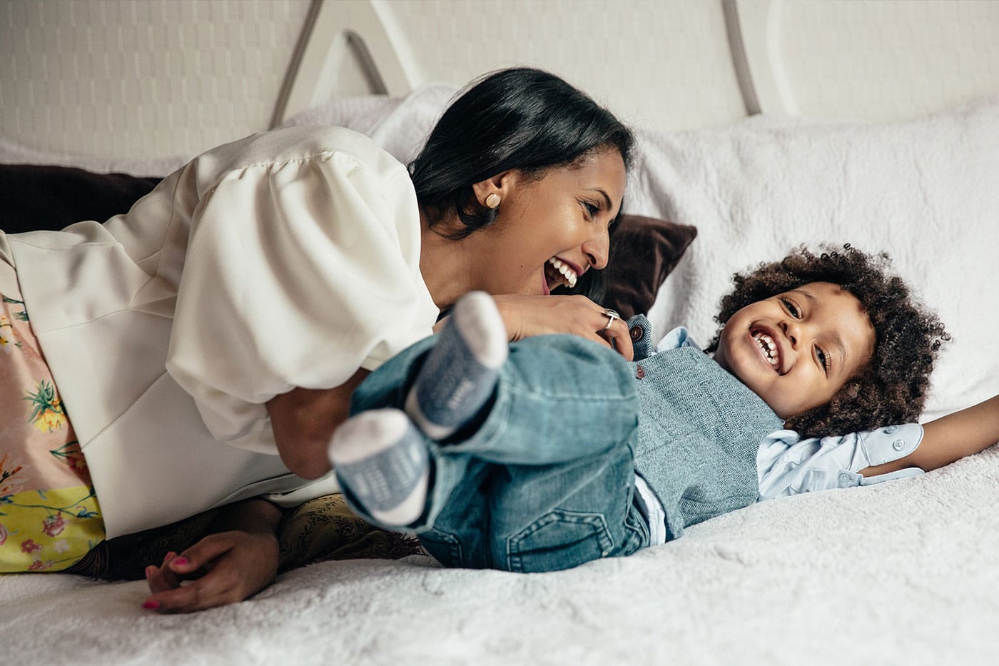 Woman tickling a child. They are both laughing.